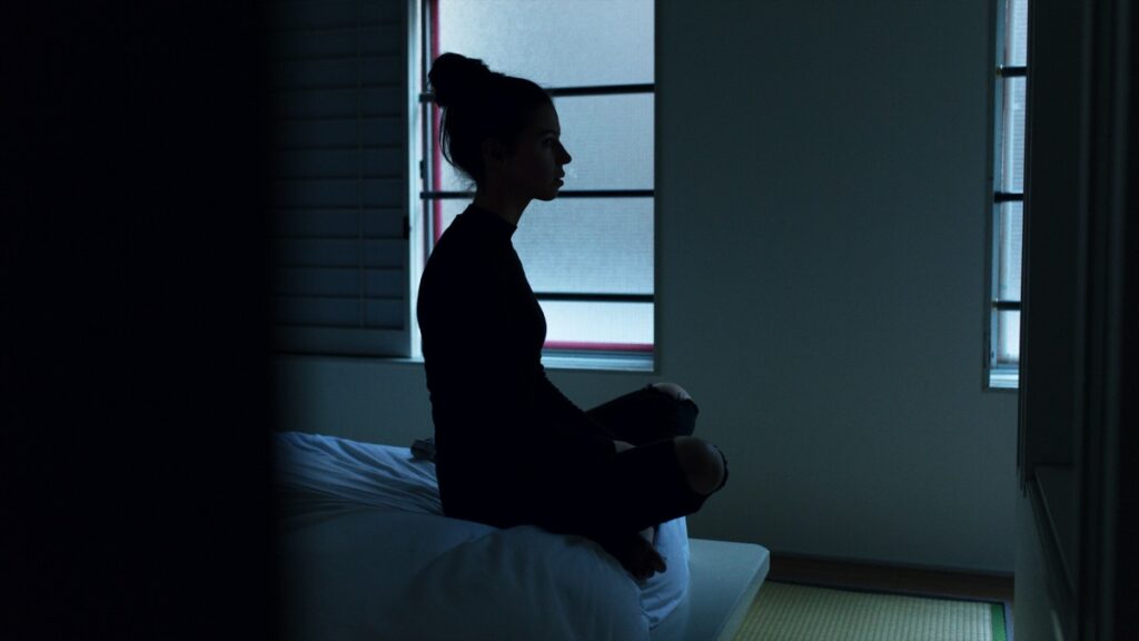 Woman on edge of bed meditating